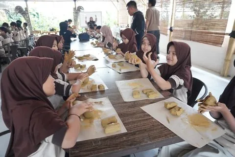 Murid SD membuat karya bersama pendamping di meja kerja